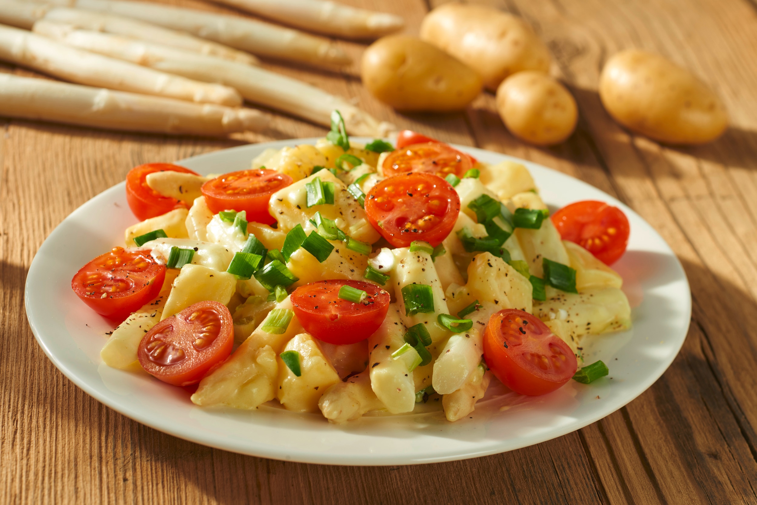 weißer Spargel mit einer cremigen hellen Sauce, Cocktailtomaten und Frühlingszwiebeln