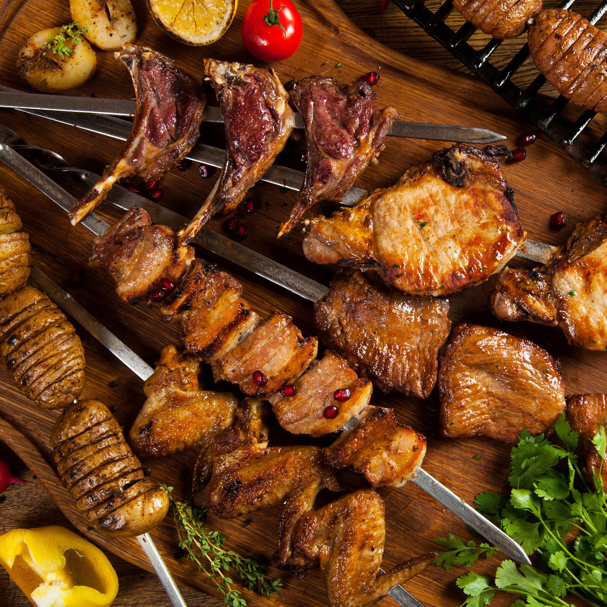 Meat on steel kebab skewers on a wooden table
