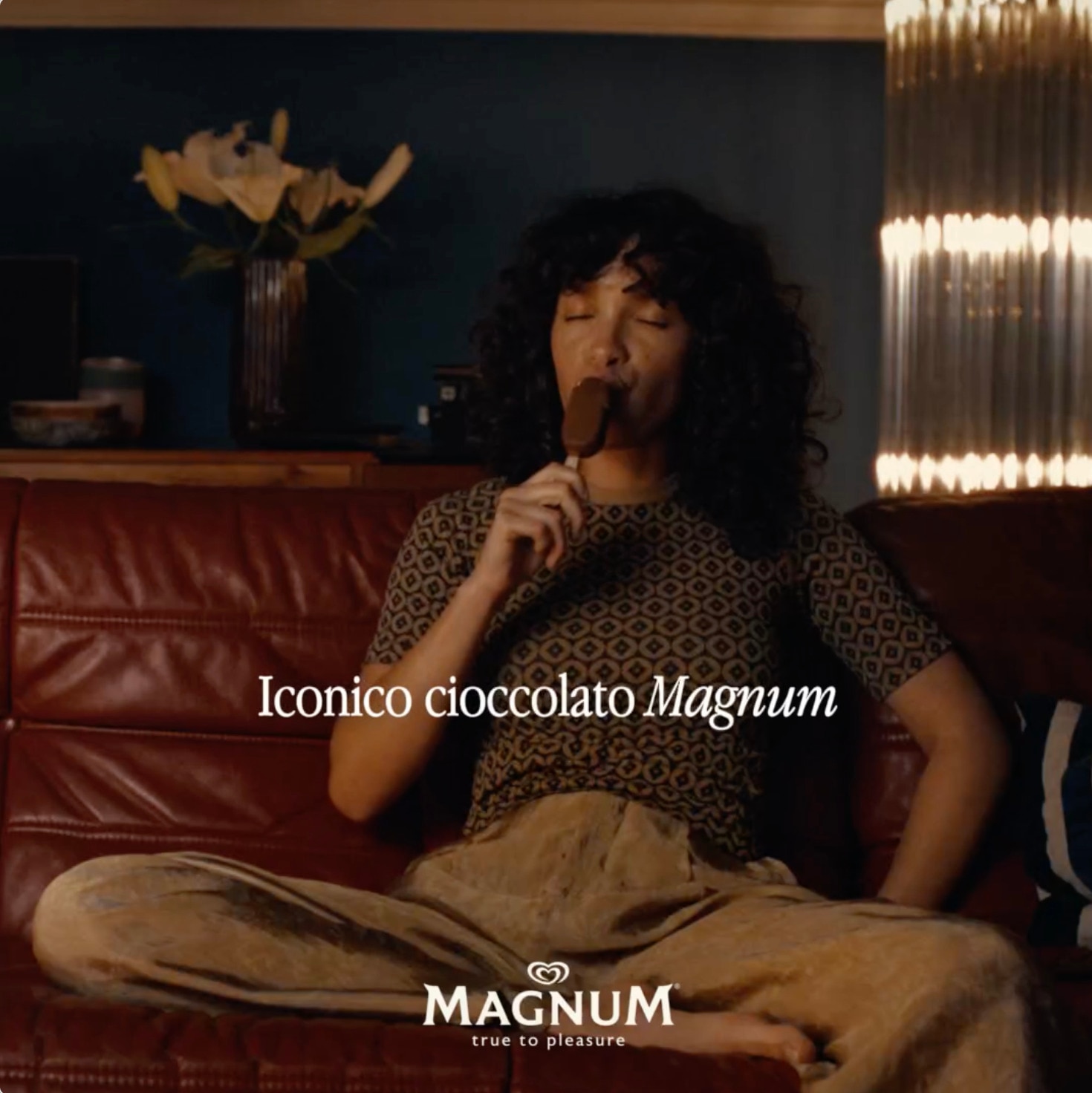Donna seduta su un divano che gusta un gelato Magnum Classico