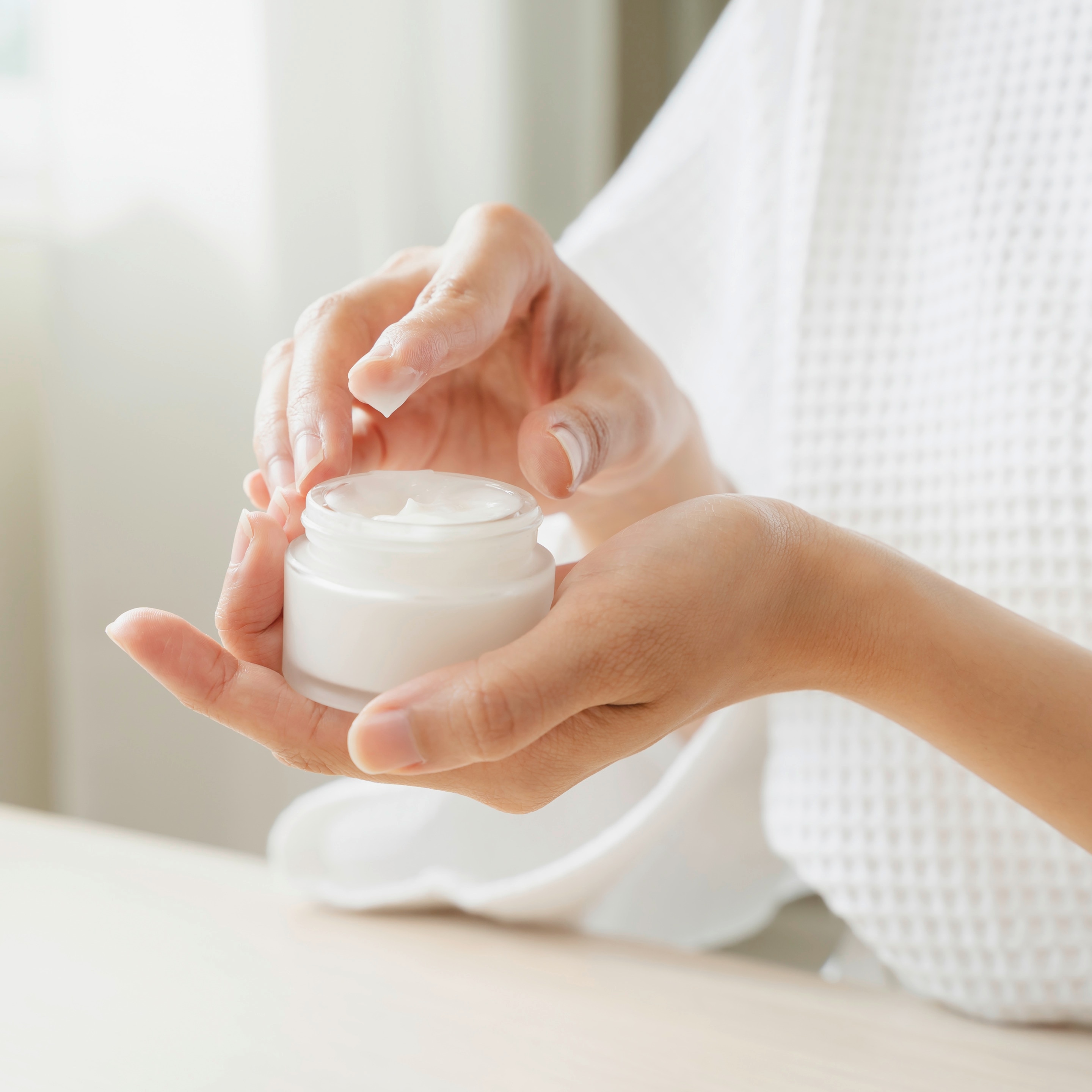 Closeup of woman’s hand holding face cream.