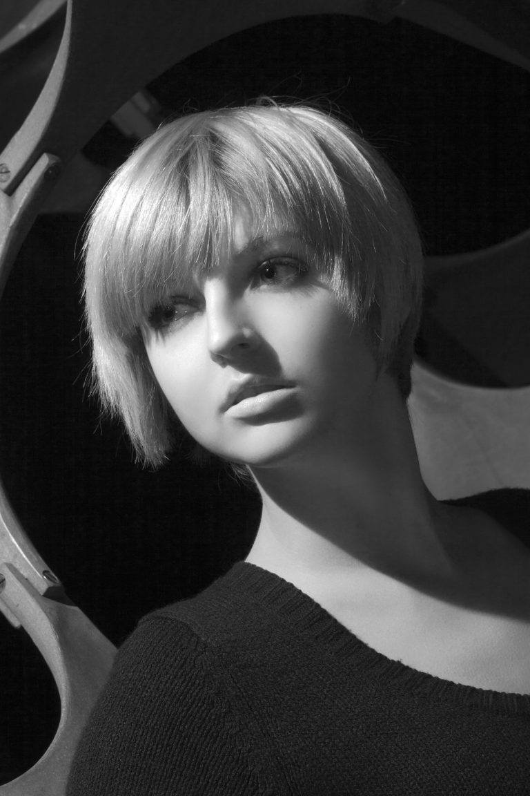 Short hairstyles: Woman in black and white with straight blonde hair in choppy mod inspired cut with bangs.