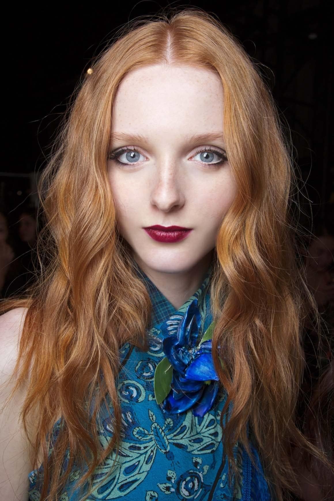 Model with long wavy ginger balayage hair wearing a blue top.