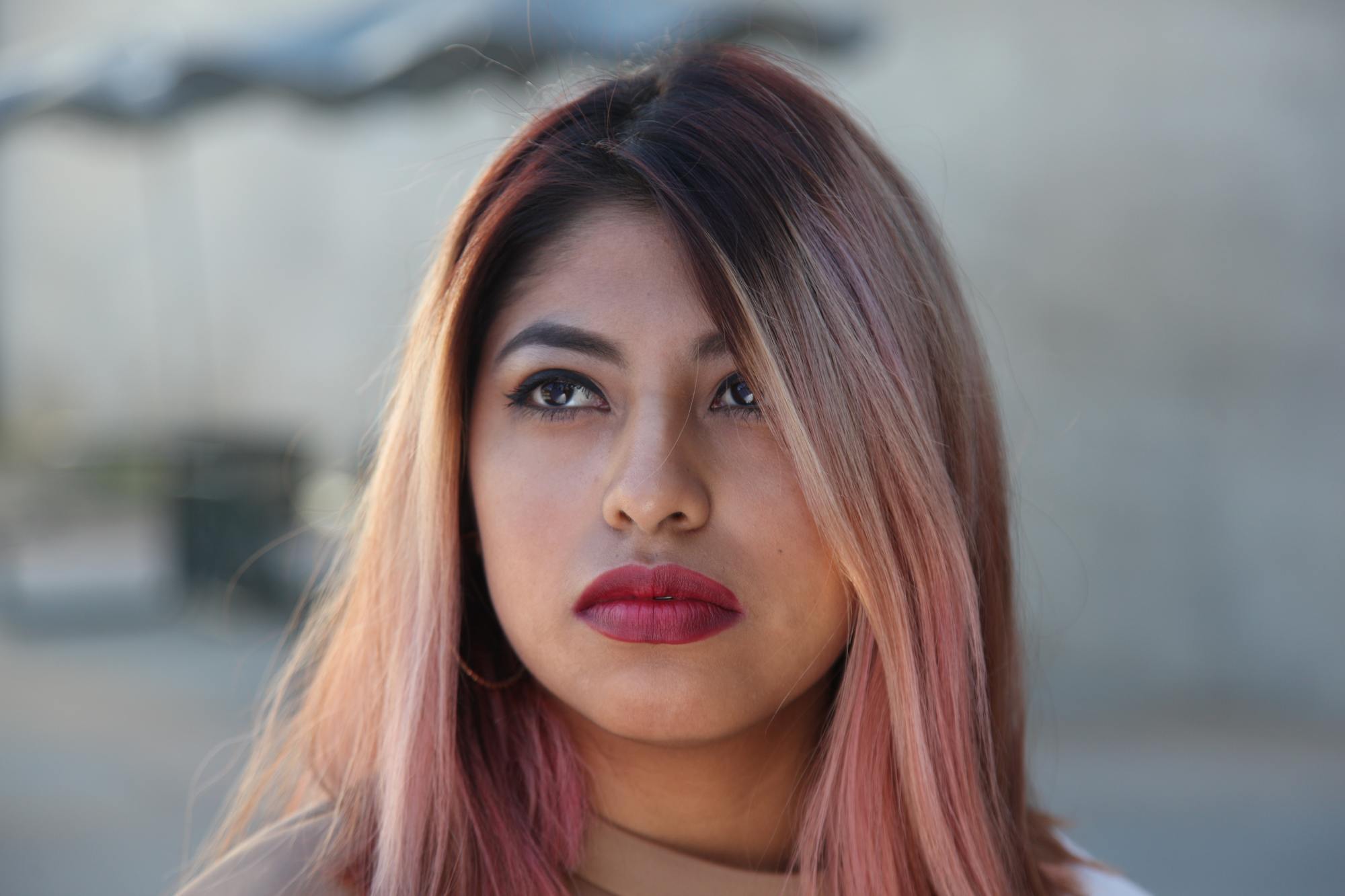 woman with dark roots and rose gold pink hair