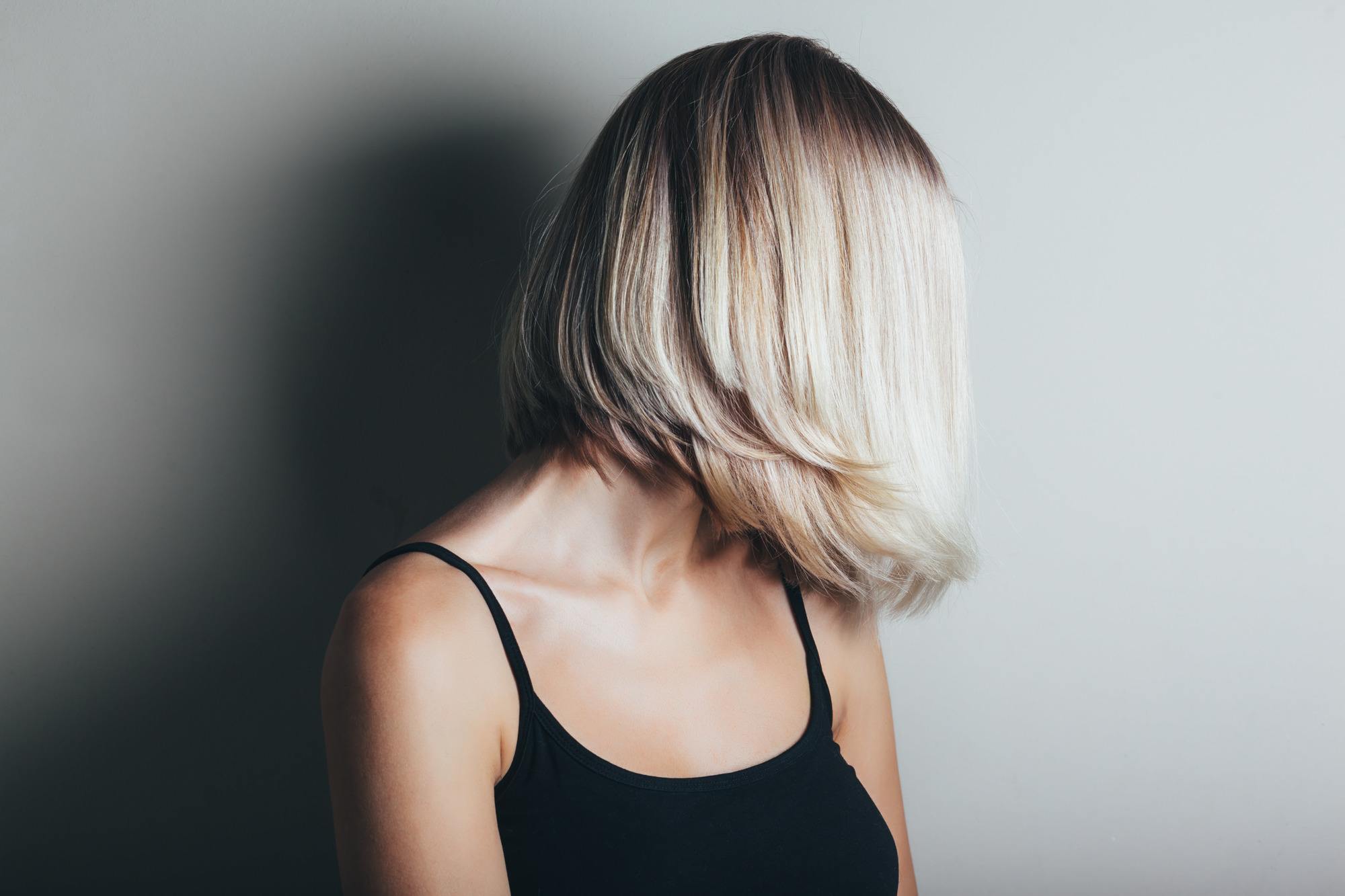 woman with bob haircut with dark roots and light blonde hair