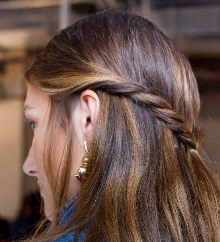 Medium hairstyles: Woman with brown highlighted straight hair in twisted half-up, half-down hairstyle.