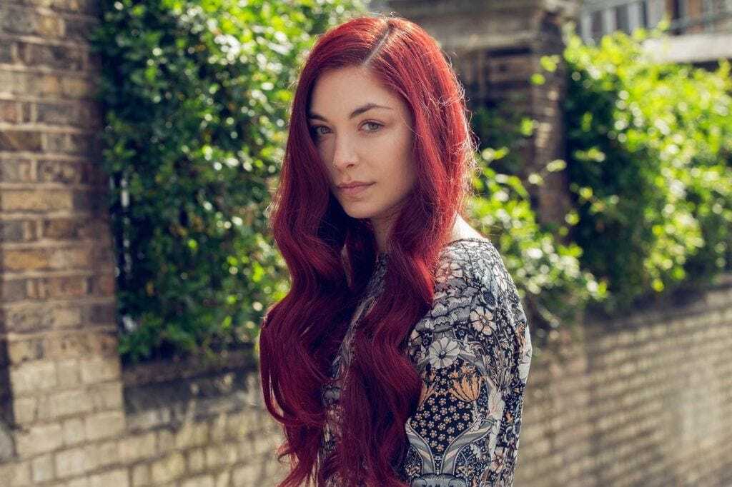 Red hair: Woman with very long wavy cherry red hair wearing a floral dress.