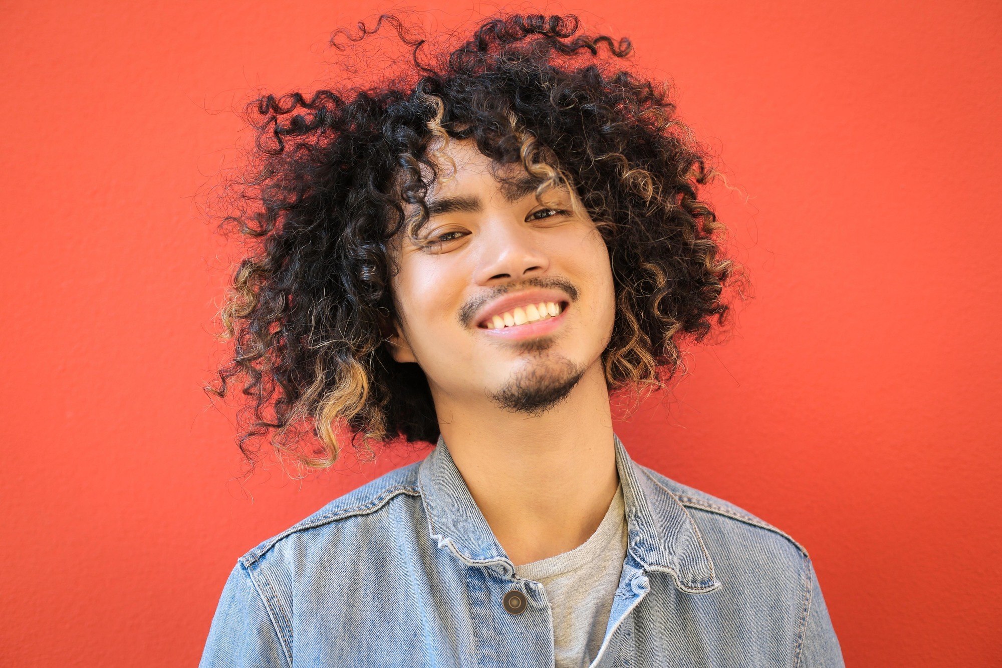 Man with curly blonde highlights as a curly hairstyle for men