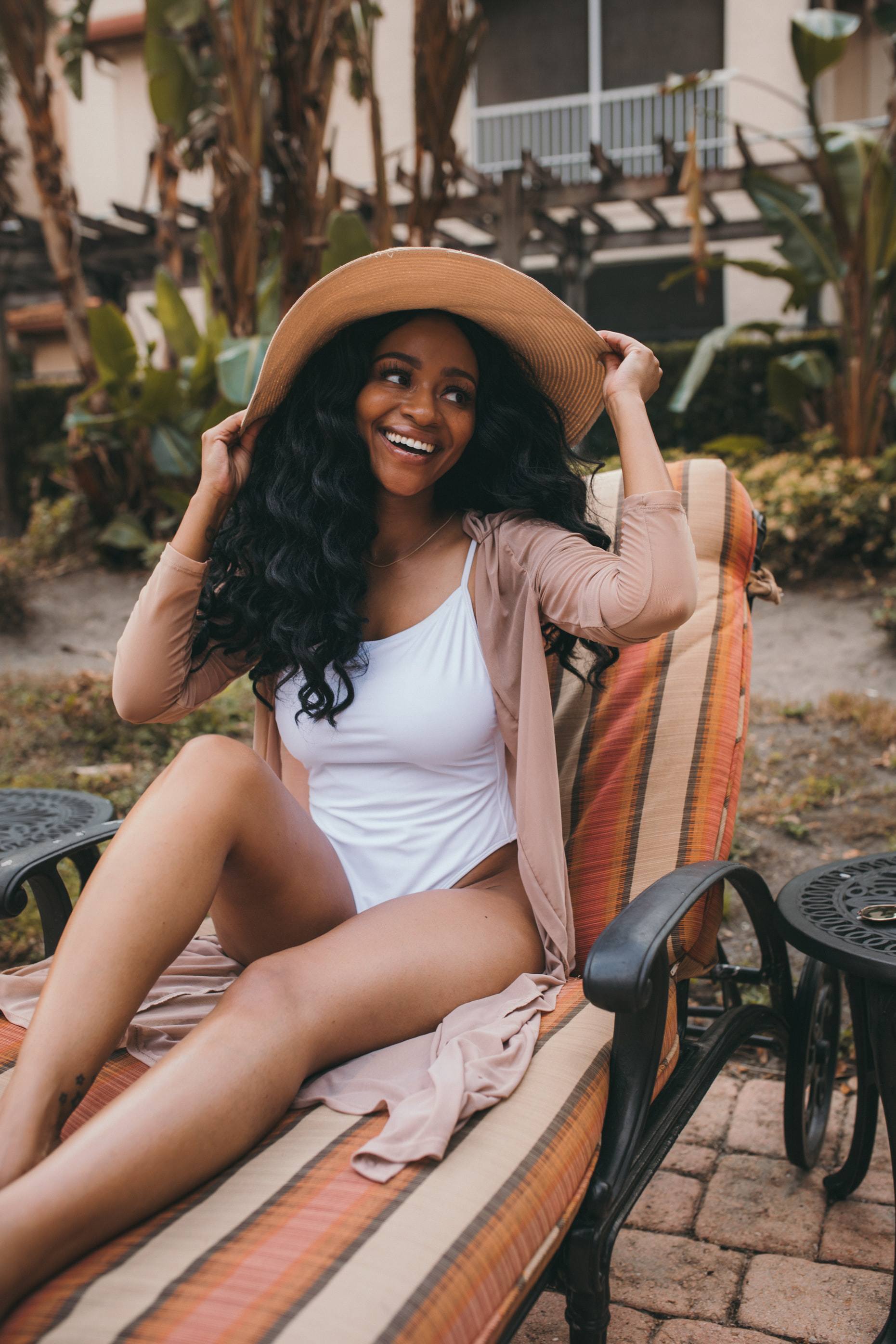 hair products for summer: woman sitting in the sun, wearing a wide-brimmed hat