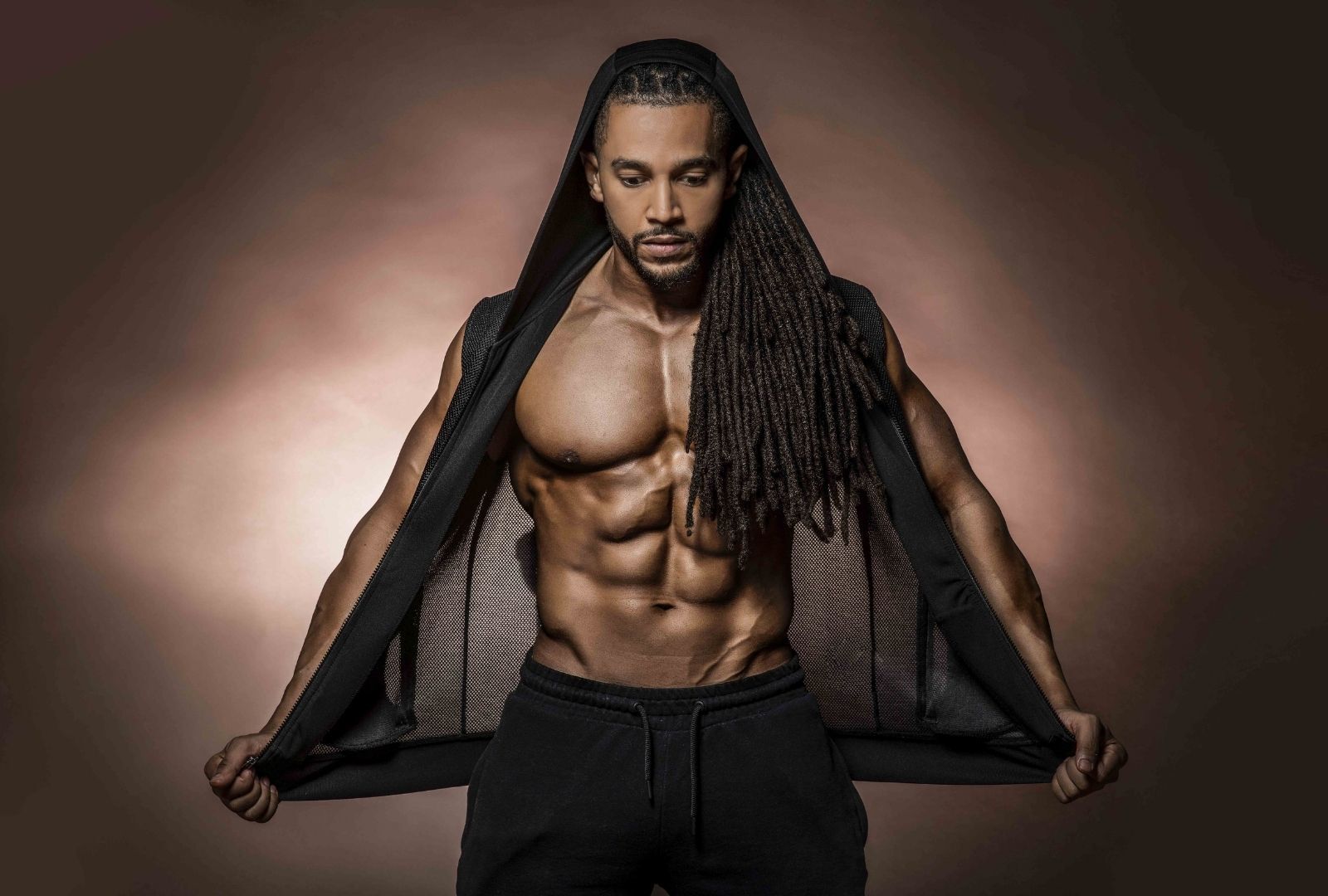 man with long thin locs styled tied back and over one shoulder