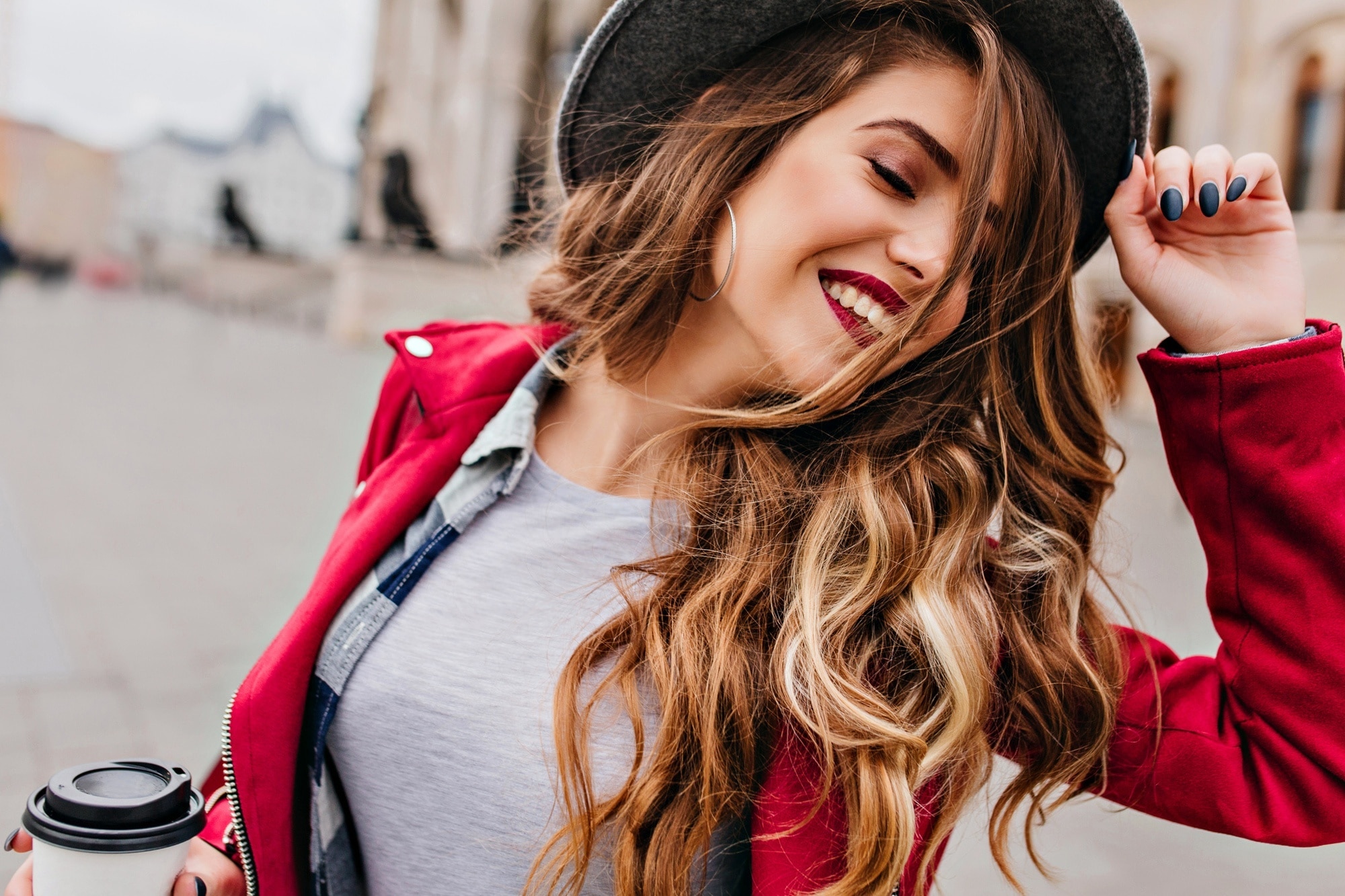 woman with wavy hair wearing a hat