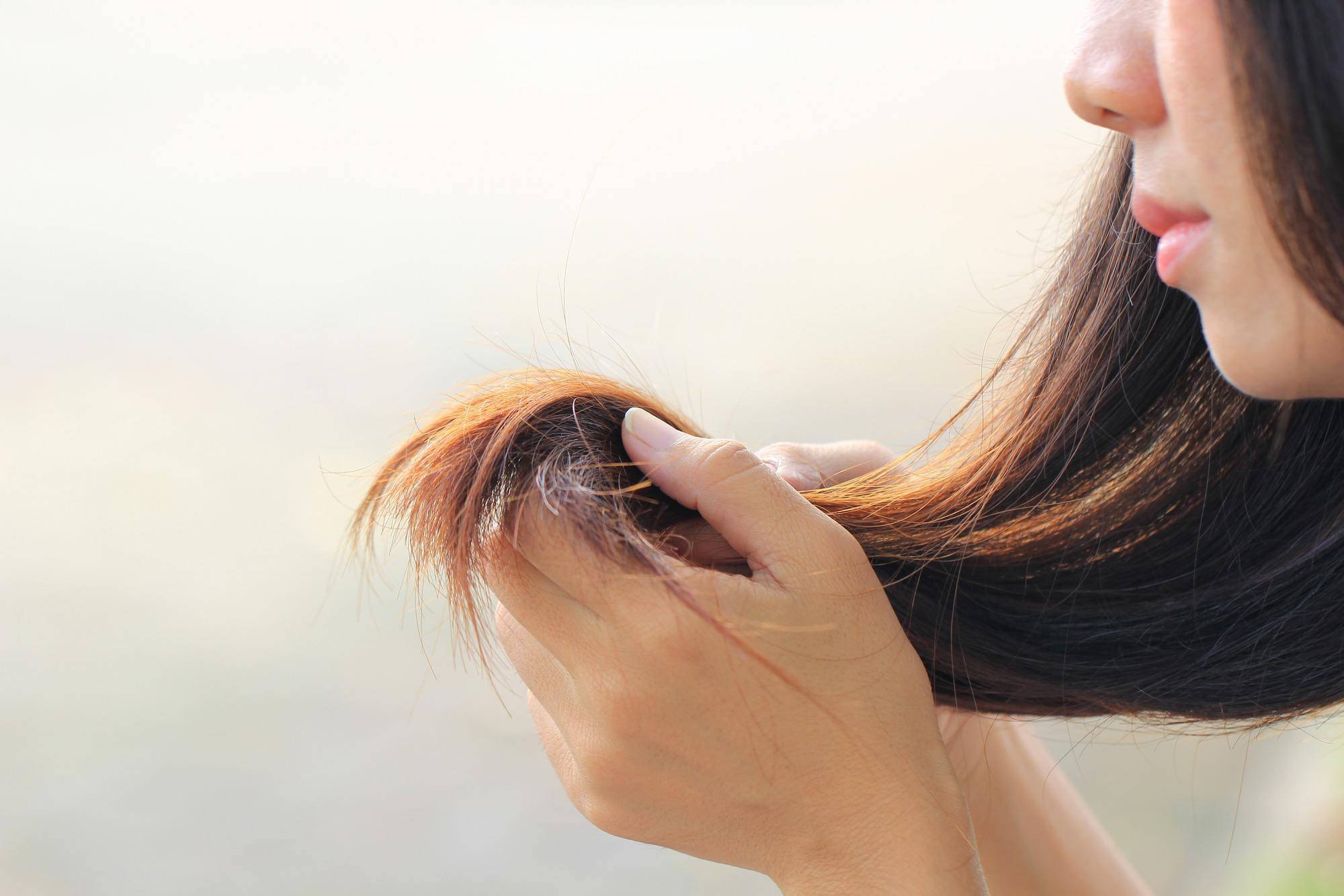 a woman looking at her hair closely