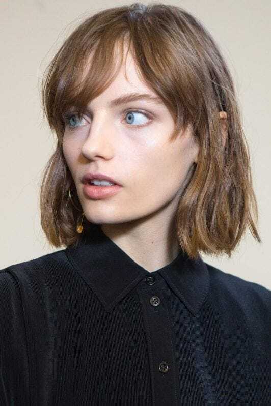 Hair types: Woman with light brown bob length hair with bangs wearing a black shirt.