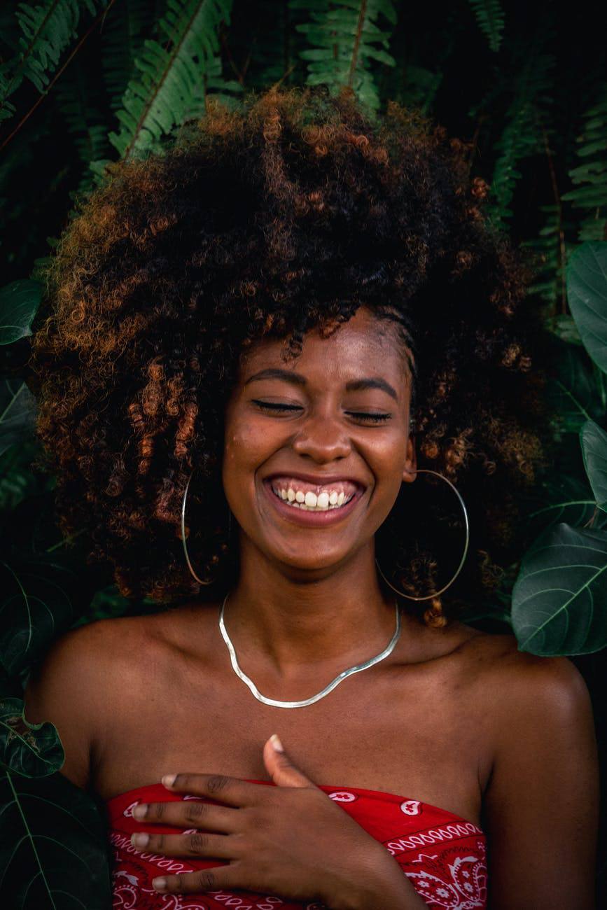 smiling woman with afro dark roots highlights