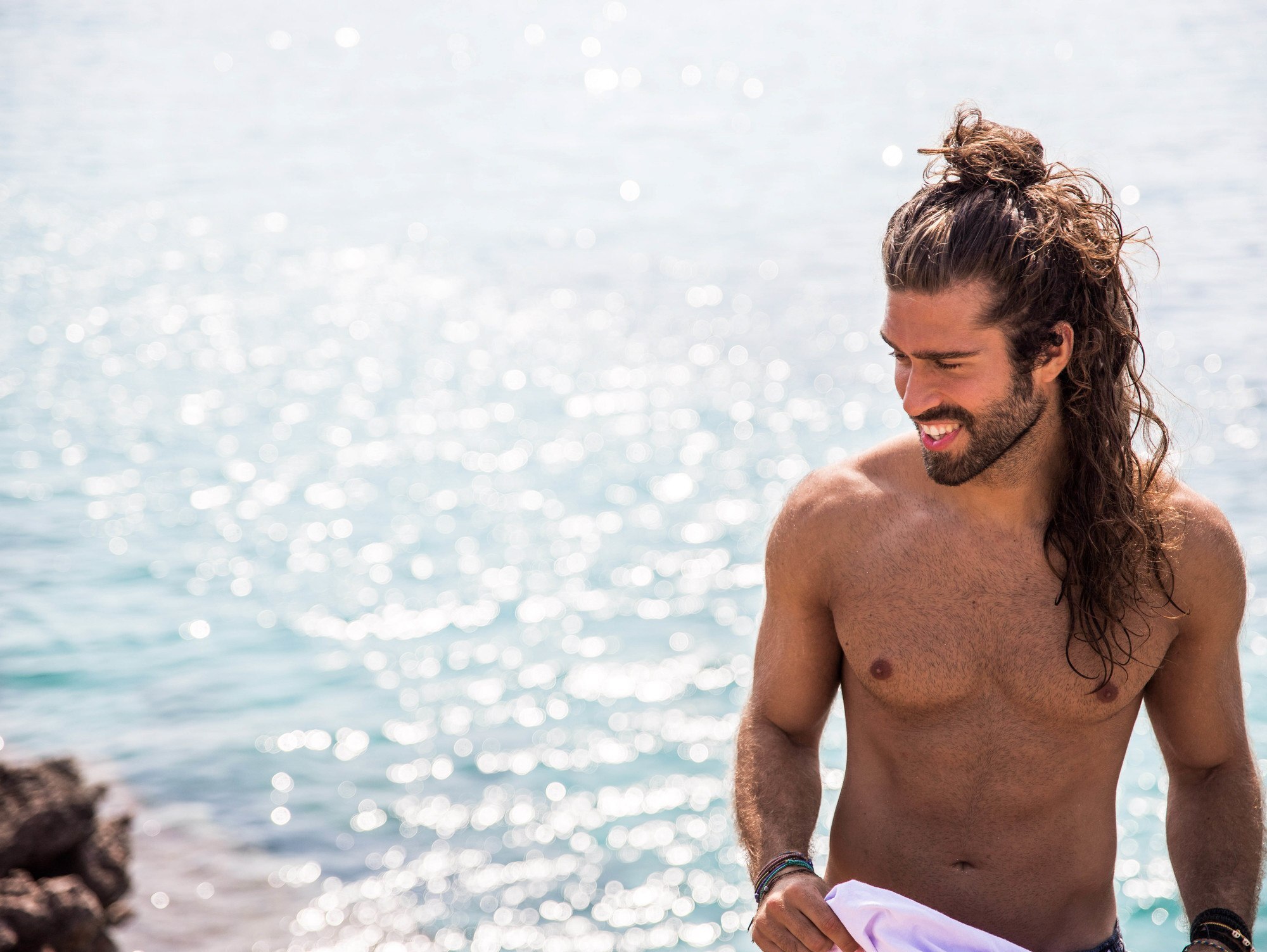 Man at the beach wearing a half up man bun