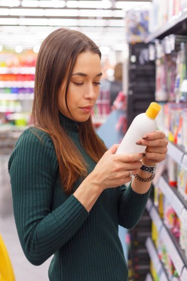 woman standing in a store, looking at hair products