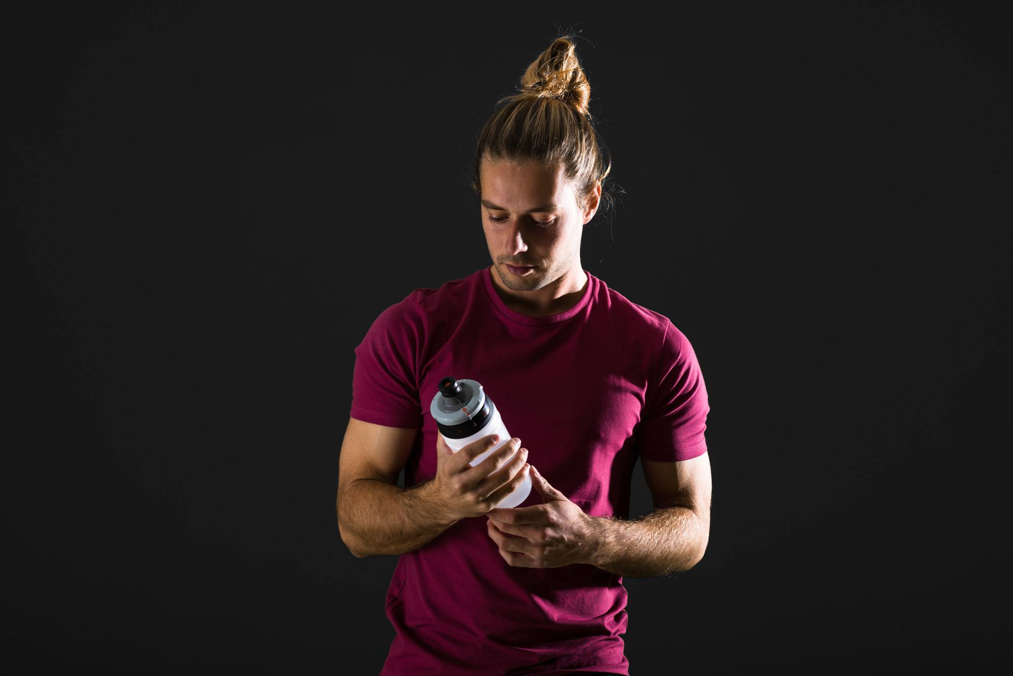 Man with a sporty man bun holding a water bottle
