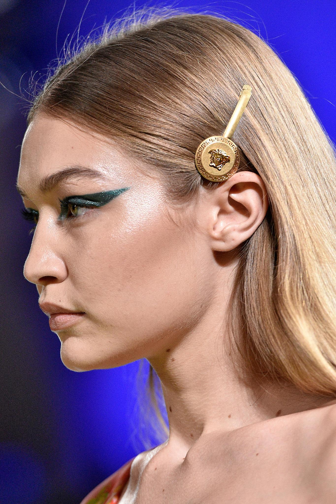 New hairstyle: Gigi Hadid with Versace hair slide on her straight blonde hair at Versace SS19 show.