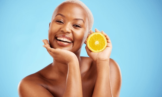 Young African American women holding a lemon for vitamin C benefits and skin brightening 