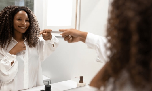 African American woman in her bathroom choosing between antiperspirant and deodorant
