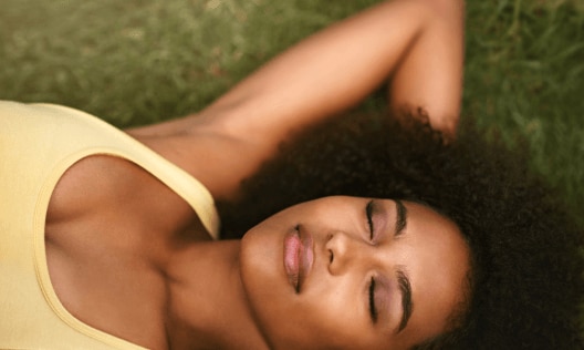 Happy young African American woman laying on the grass feeling happy confident and comfortable