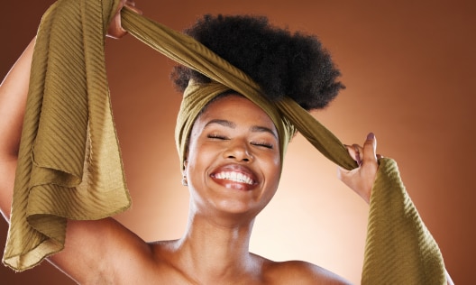 Young woman placing her hair in a head-wrap while wearing deodorant for sensitive skin