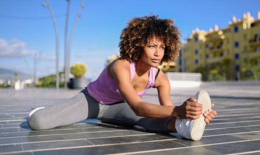 Young African American woman doing stretches after a run while wearing whole body deodorant