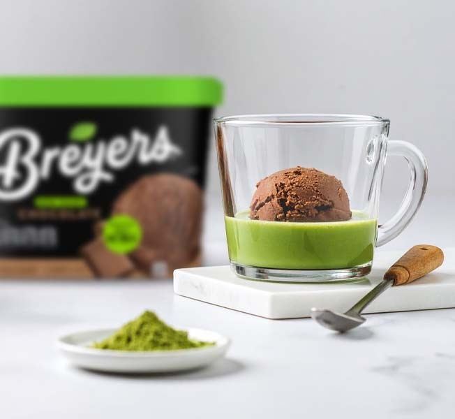 A chocolate matcha affogato in a clear mug placed on a marble coaster