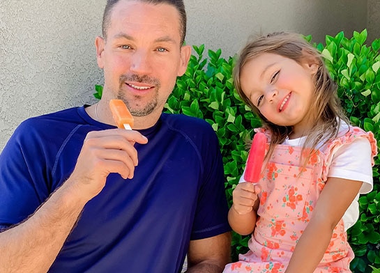 Father and daughter eating Popsicle ice pops.