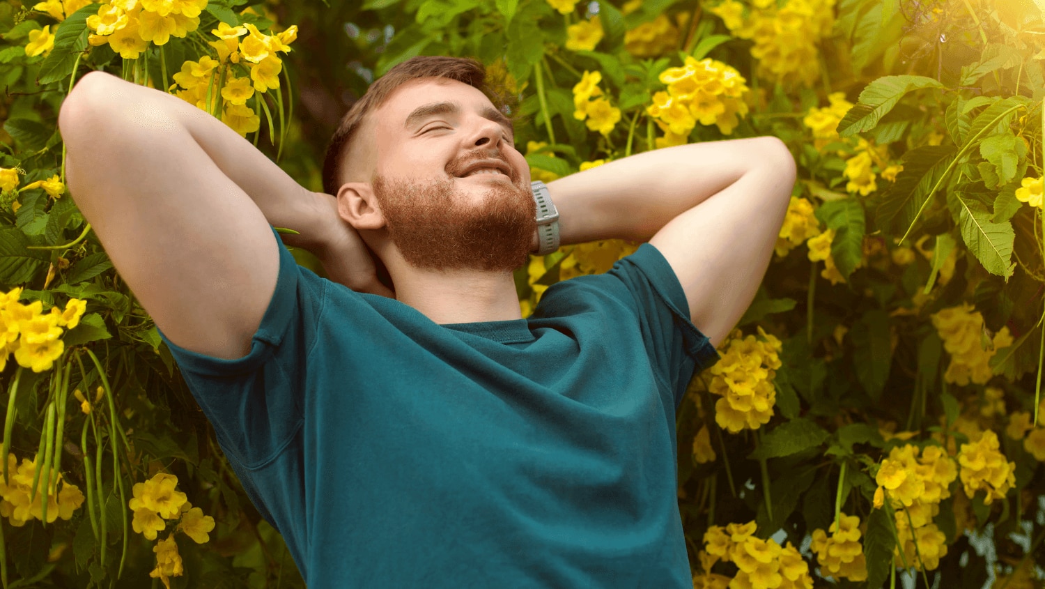 Young man sitting in a garden enjoying the floral fragrance