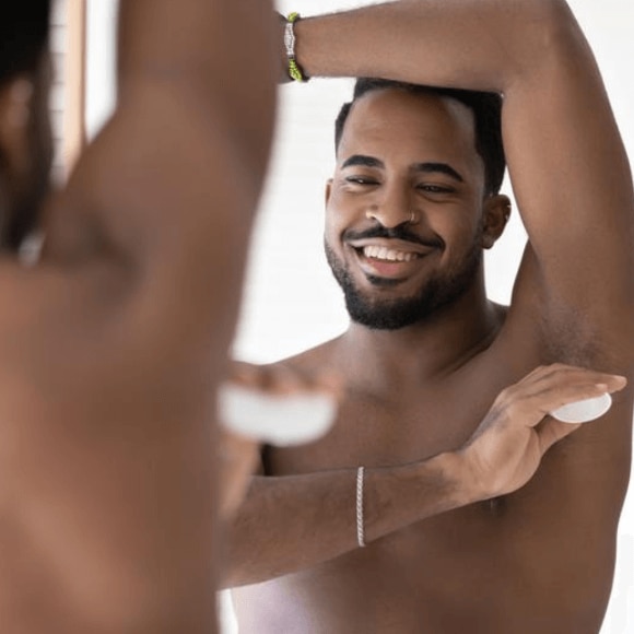 Man fresh out of the shower applying deodorant to avoid sweat after a shower