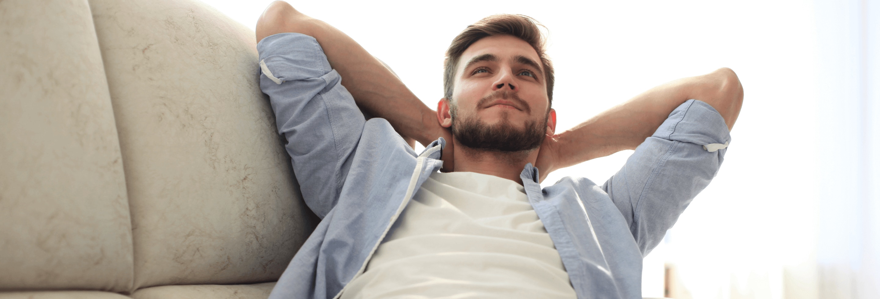 Man resting on couch with his armpits showing, wondering about body odor