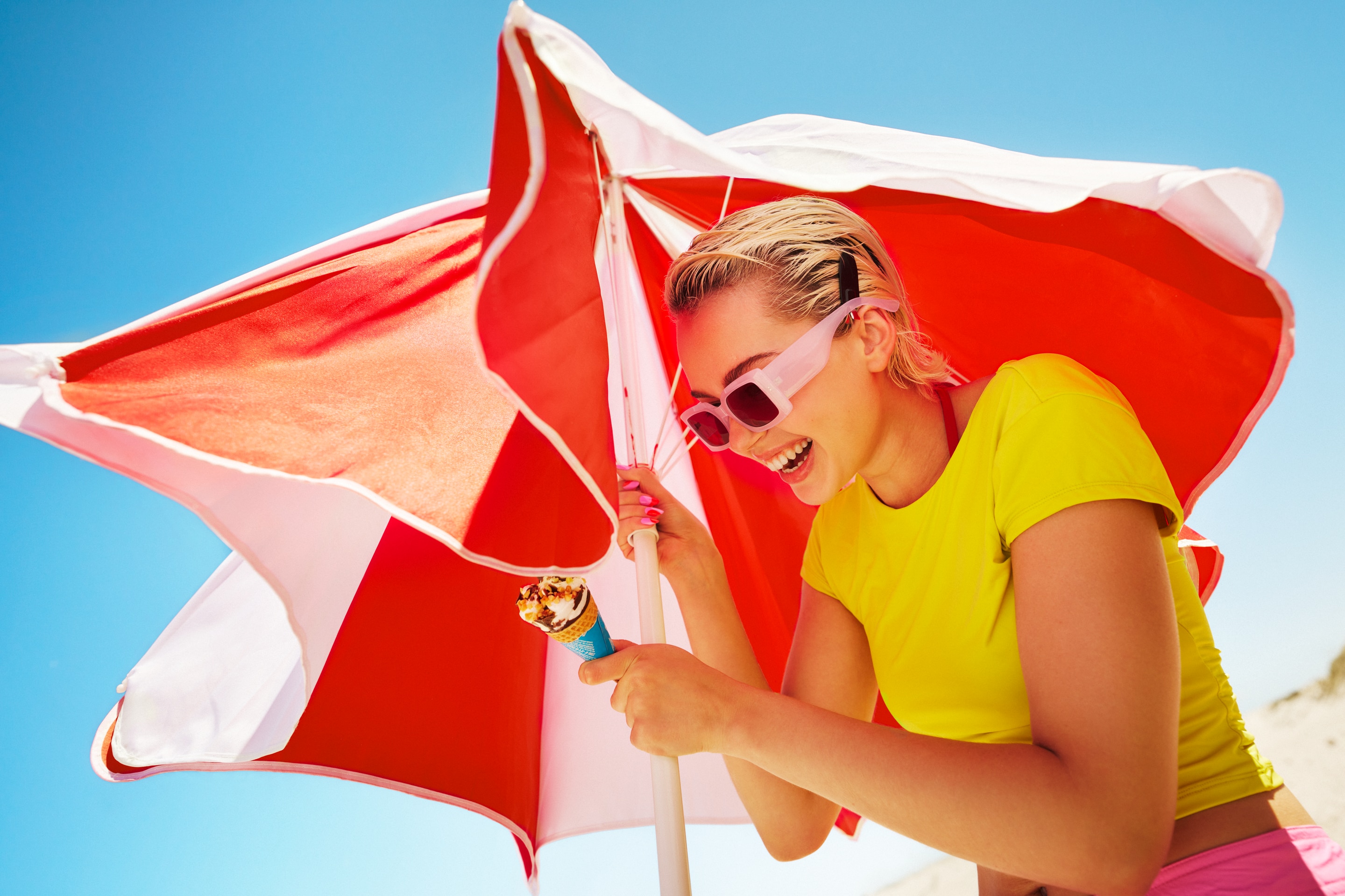 Woman holding a beach umbrella and a Cornetto ice cream