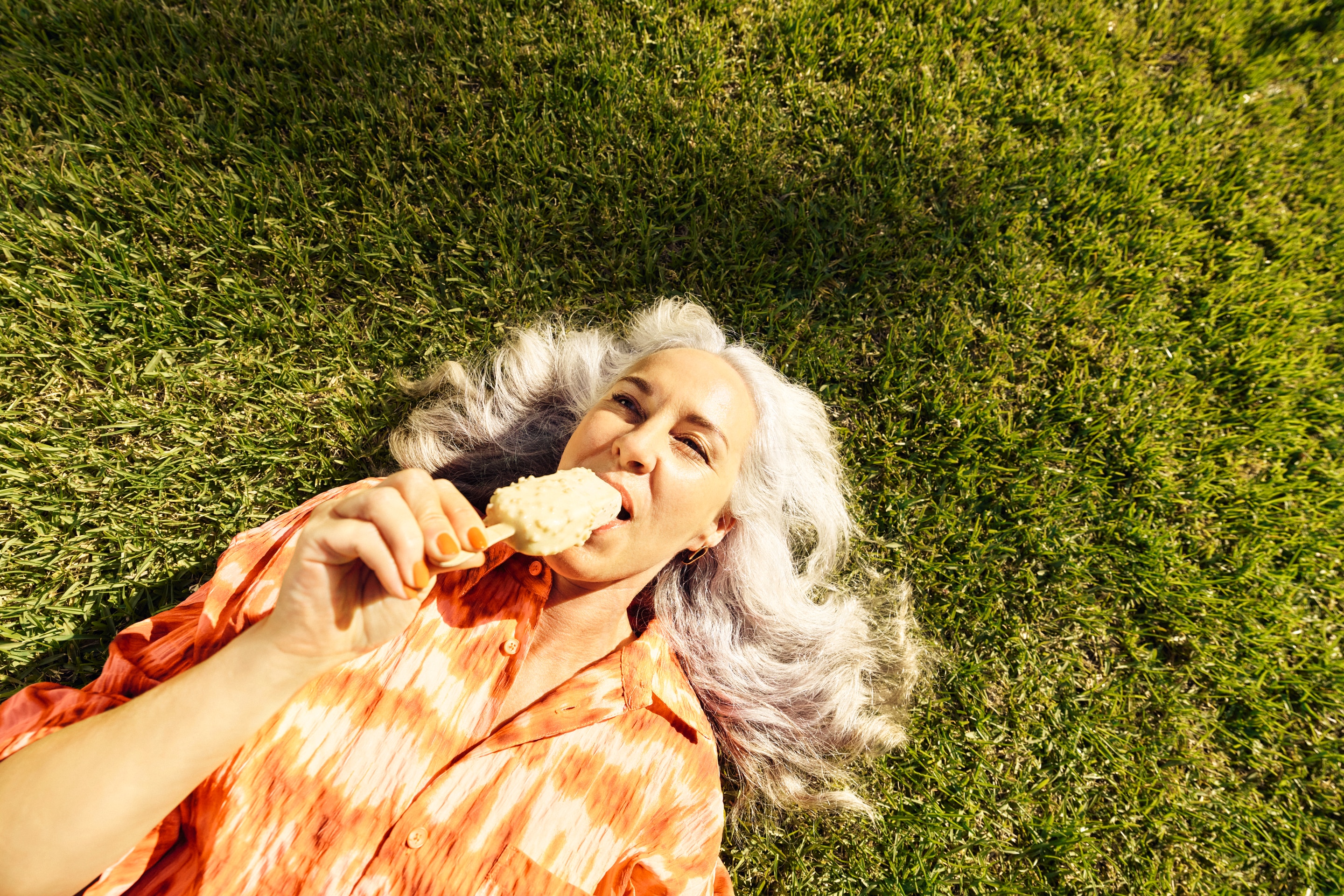 Couple smiling on the beach with an ice lolly against a blue sky