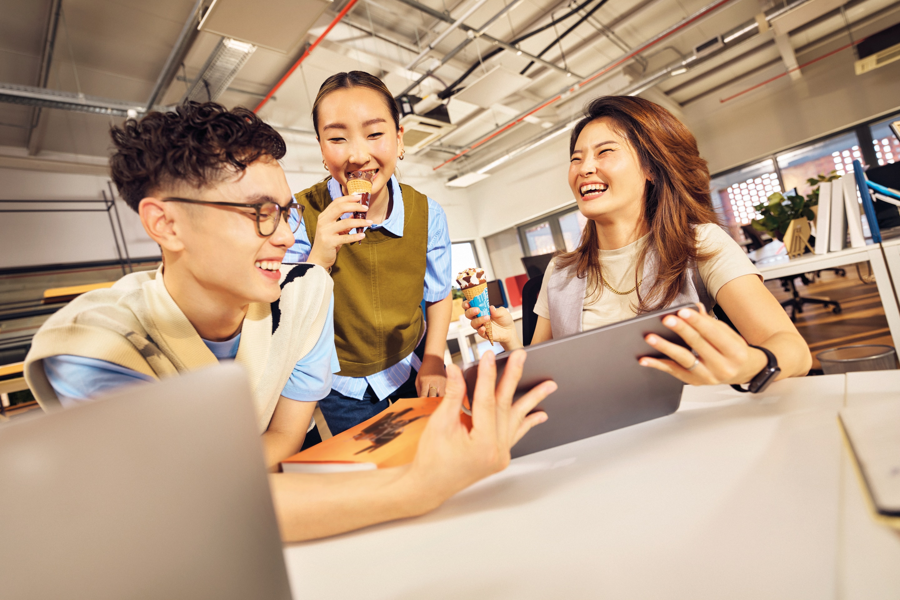 Group of colleagues in an office holding Cornetto ice creams and tablet