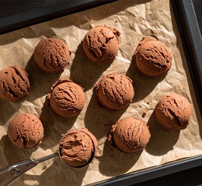 Scoops of chocolate ice cream on a baking tray.