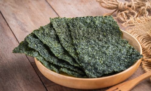 Beberapa lembar rumput laut kering diletakkan di atas mangkuk kayu.