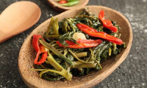 Satu piring kayu berisi tumis kangkung. menu buka puasa irit.
