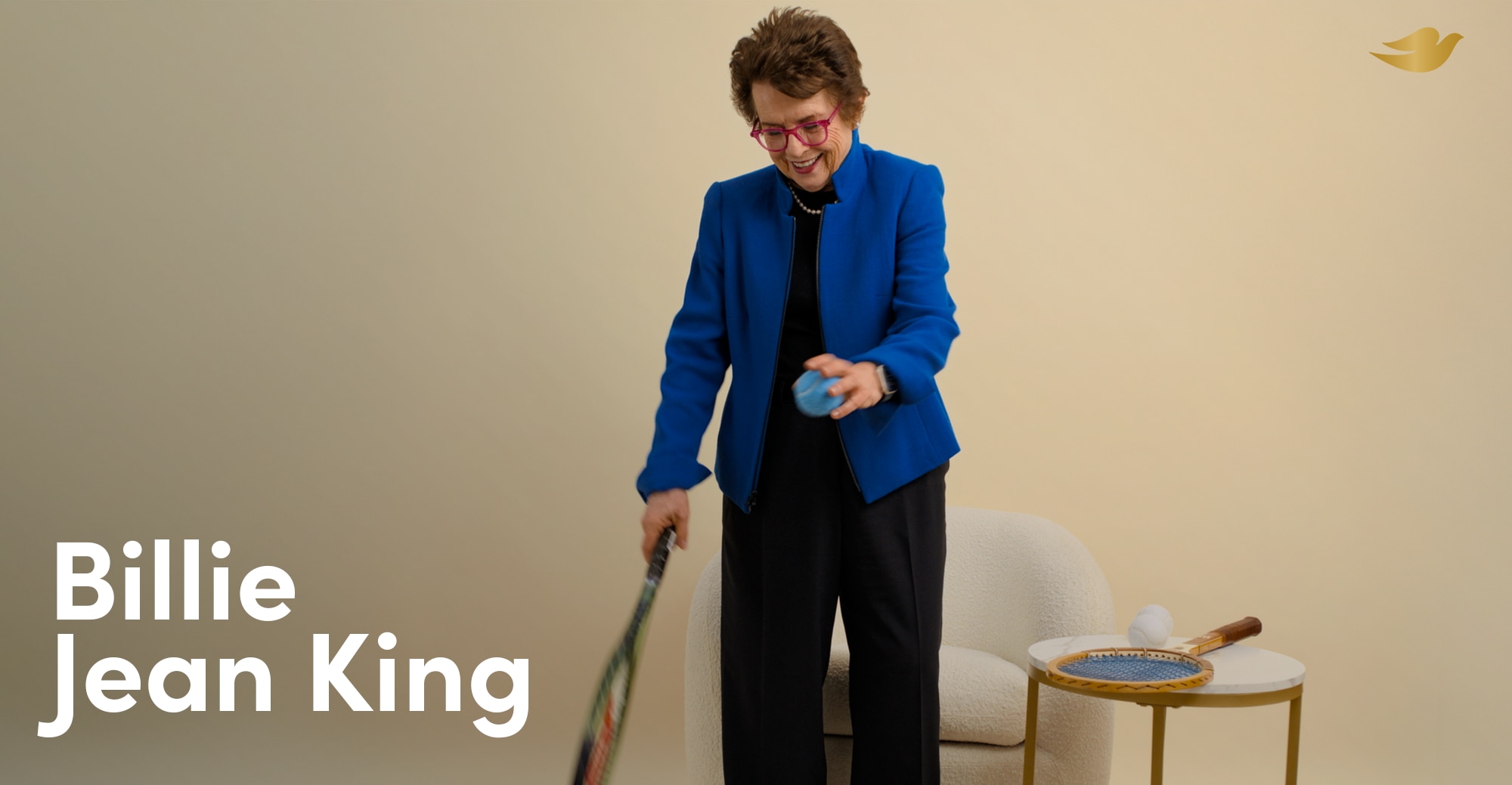 Billie Jean King smiling as she bounces a tennis ball against the floor