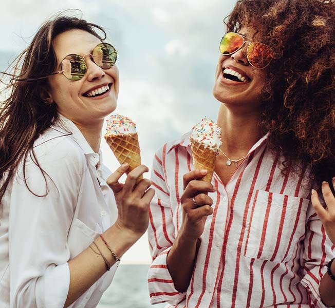Two friends having ice cream by the sea.