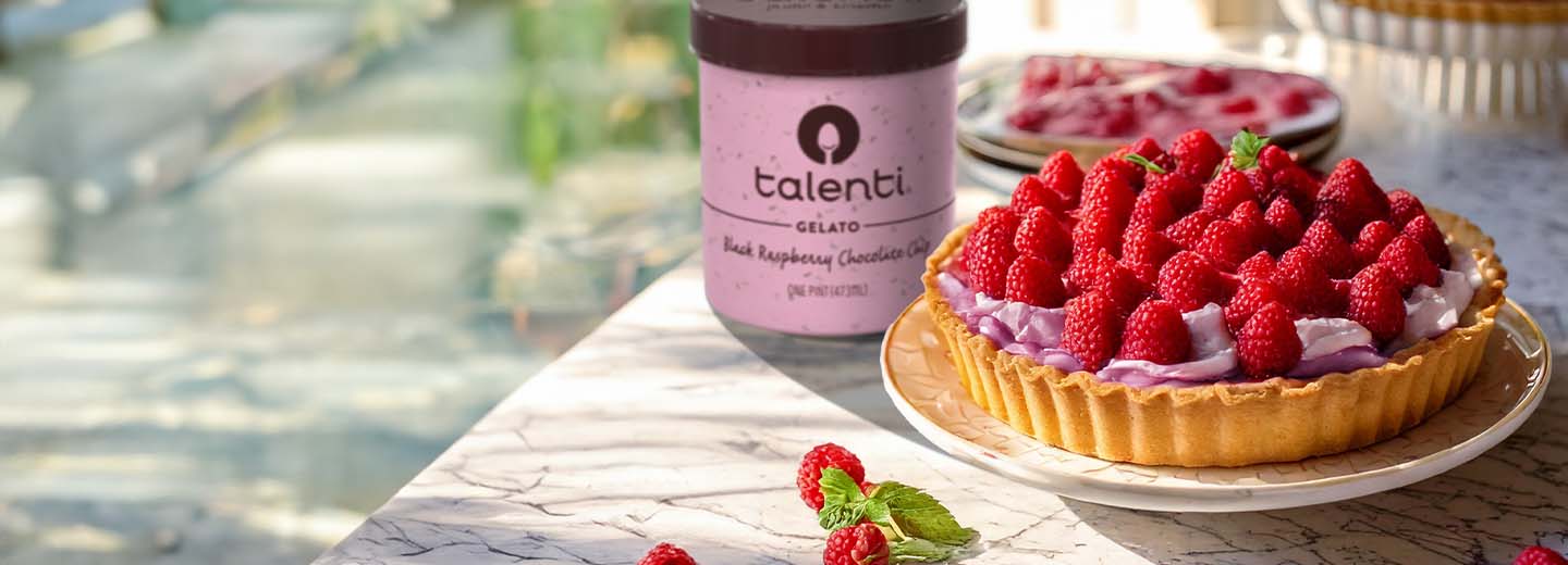 Berry gelato pie decorated with raspberries on marble table.