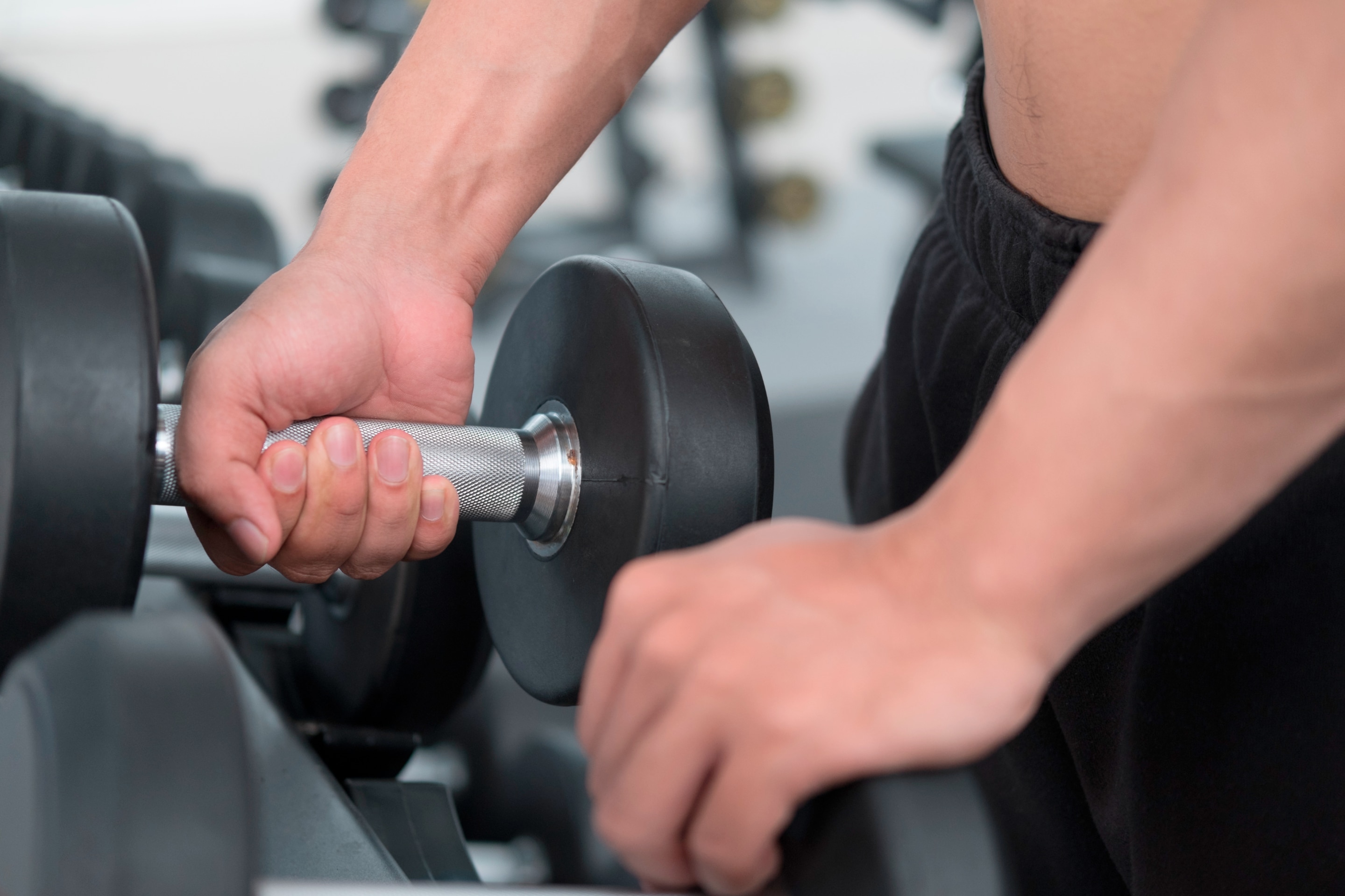 pria sedang melakukan gerakan workout di rumah berupa deadlift dengan dumbbell