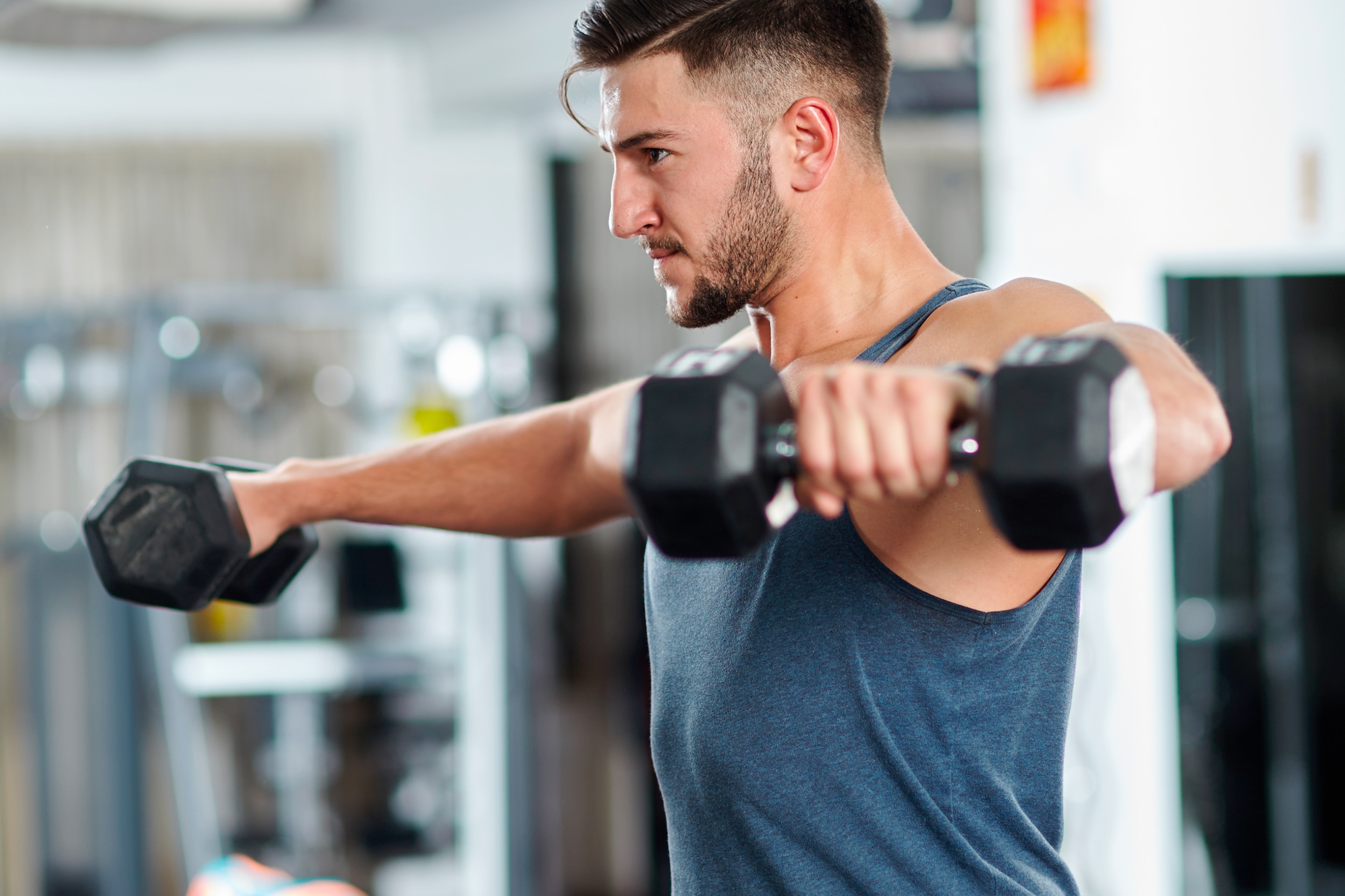pria sedang melakukan gerakan workout di rumah berupa arm circles