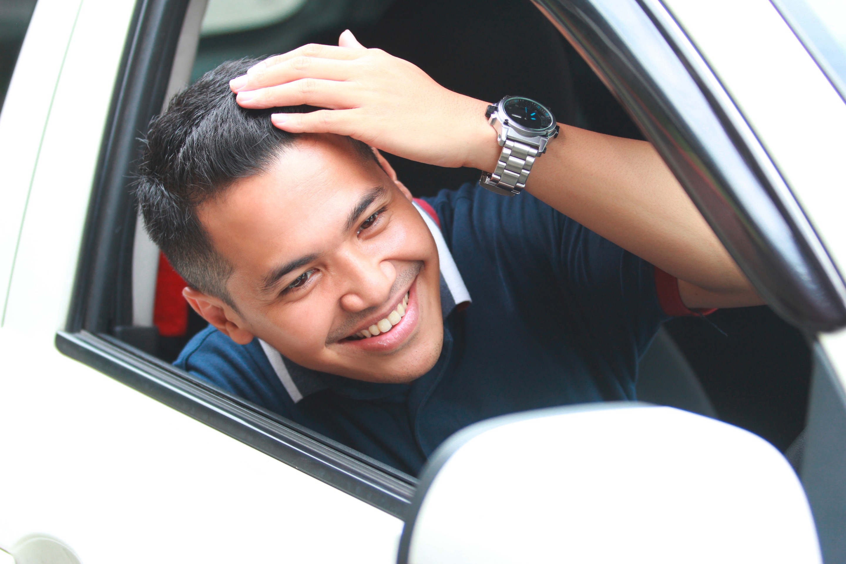Man fixing his hair in front of side car mirror.
