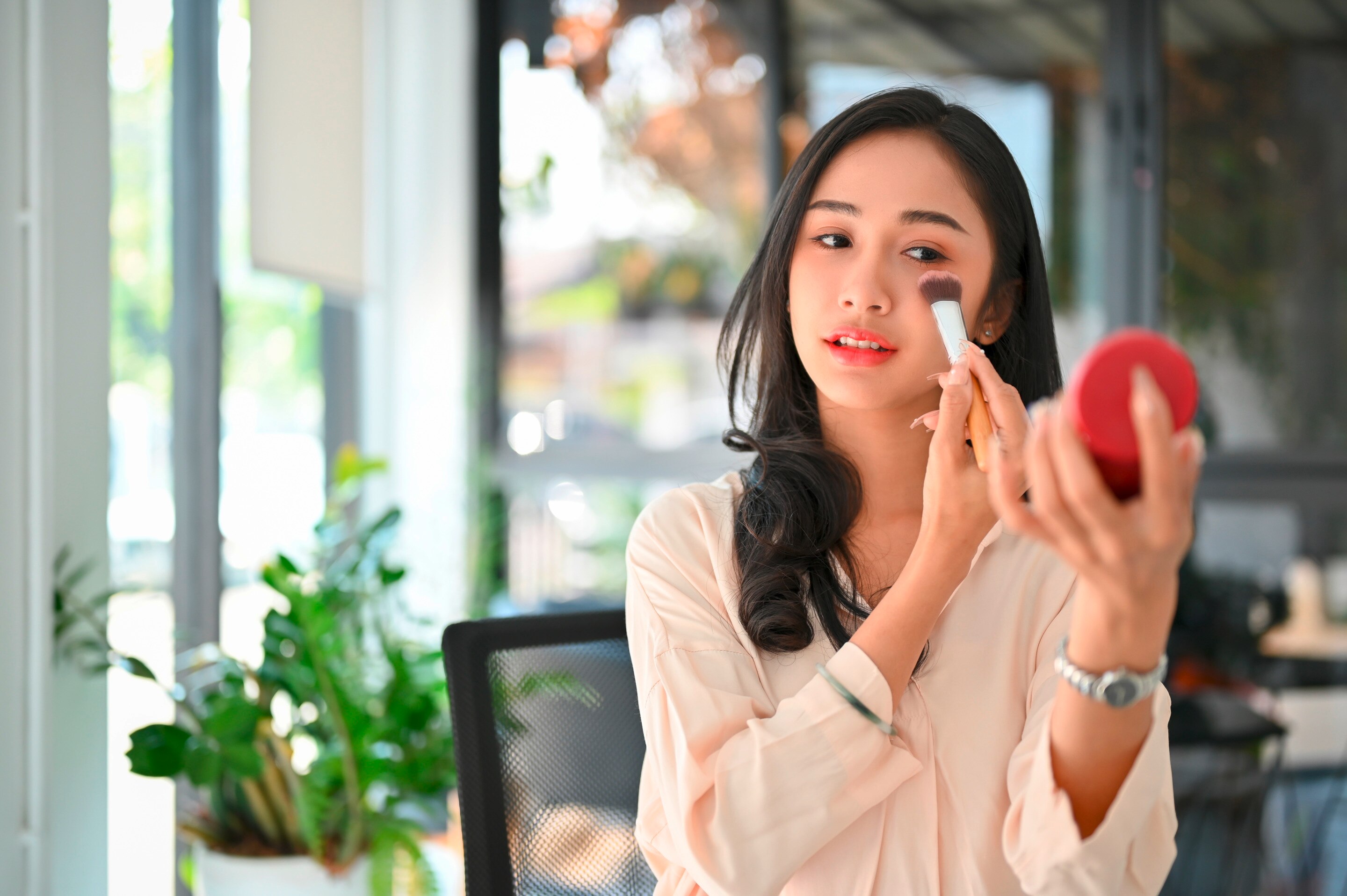 A woman putting on blush makeup.