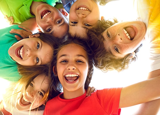 Group of smiling kids hugging in circle