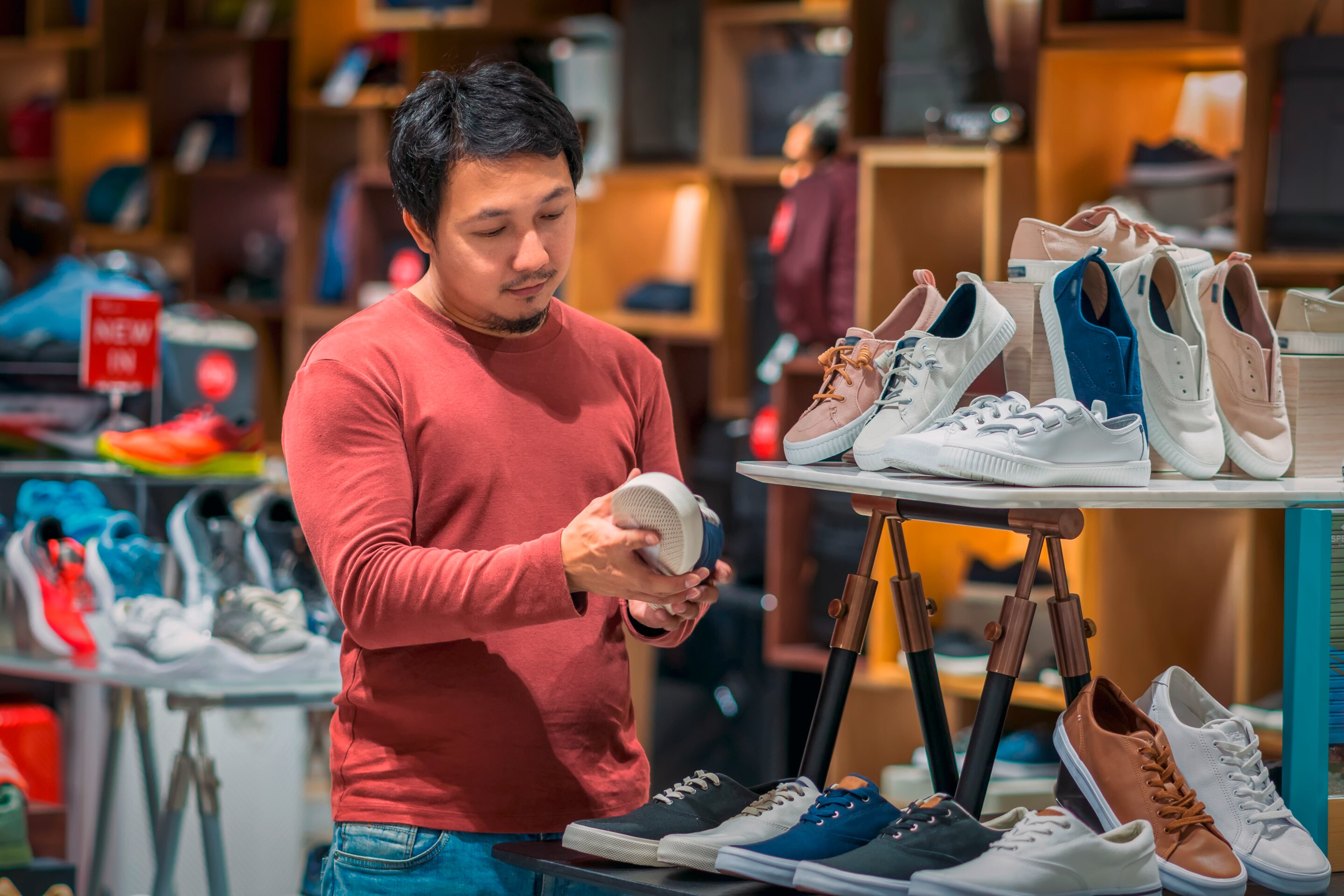 Asian man in store buying shoes.