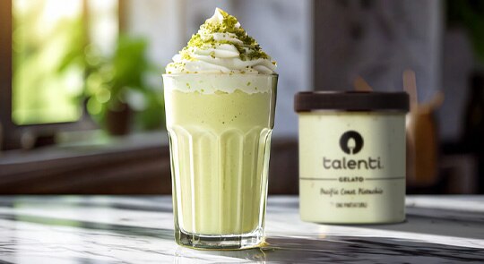 Glass of pistachio milkshake on a marble table.
