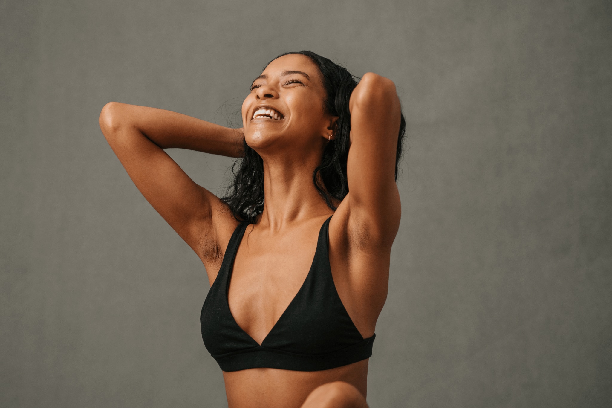 Yoga girl with her arms raised in joy revealing clear underarms