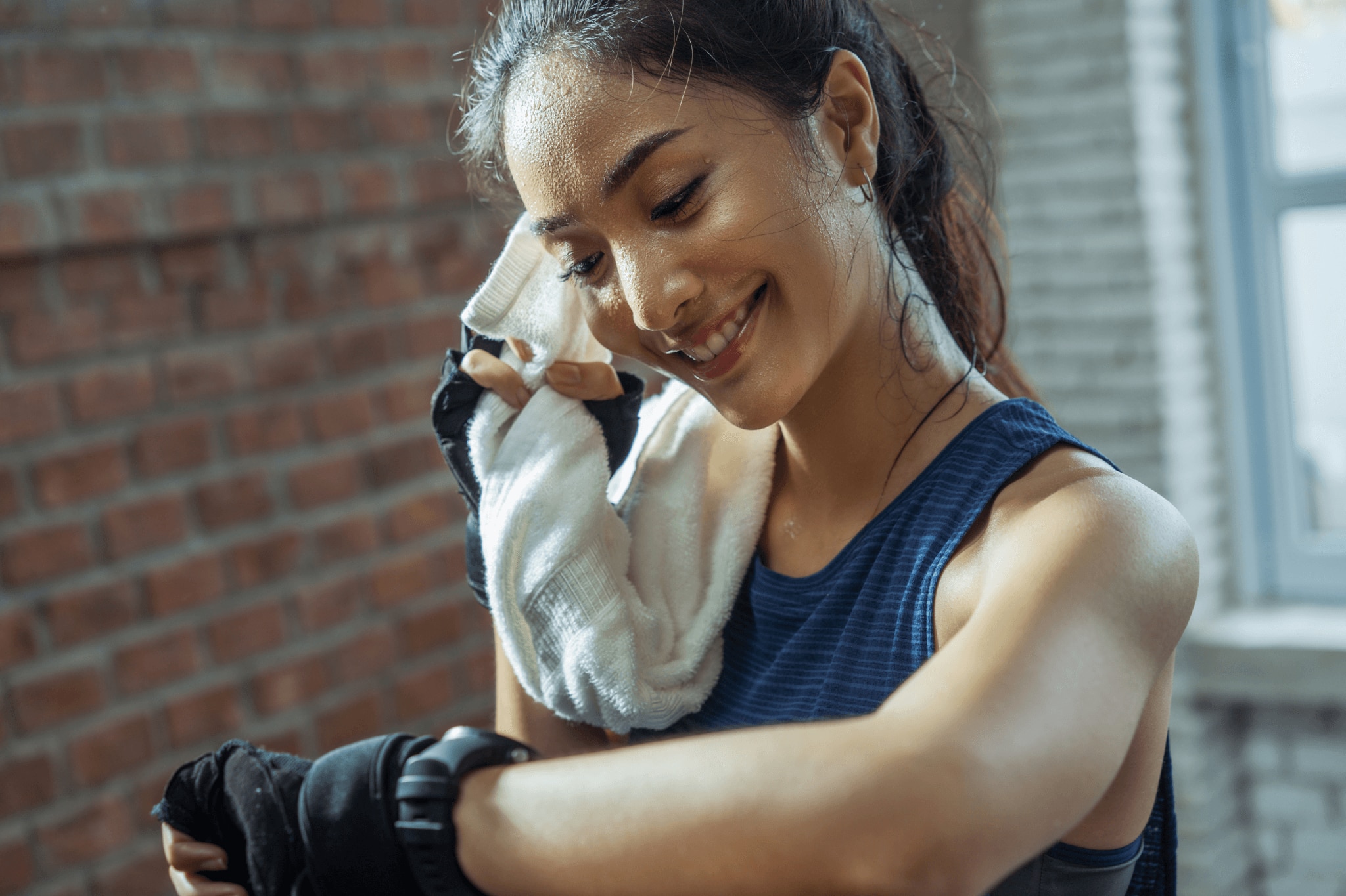 Young woman in gym clothes wiping the sweat from her face