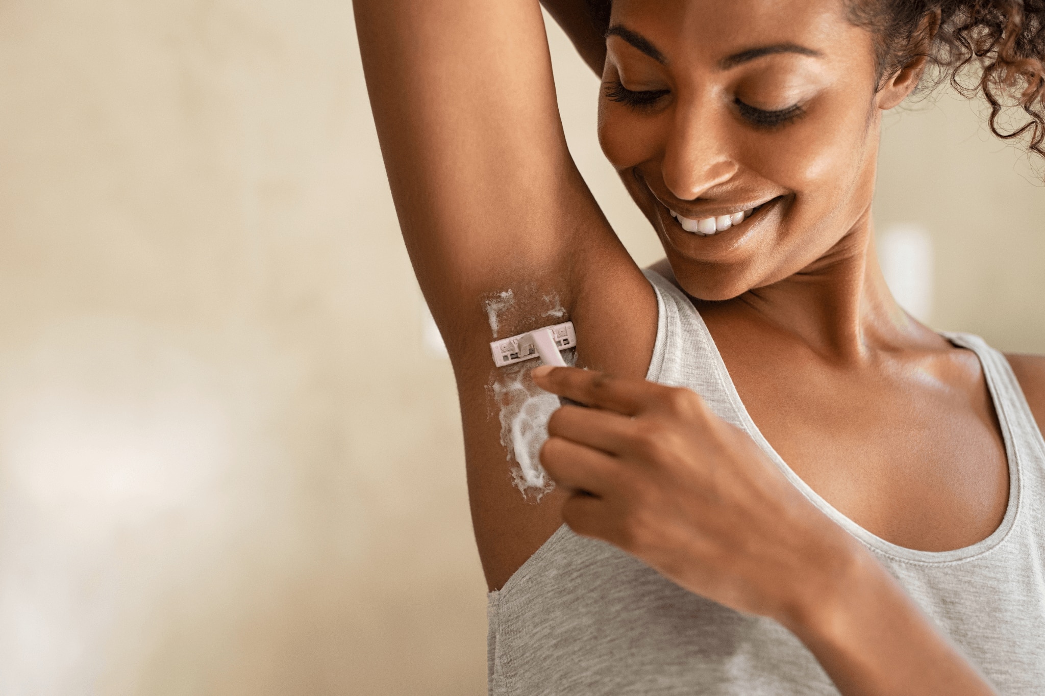 Young woman shaving her underarms
